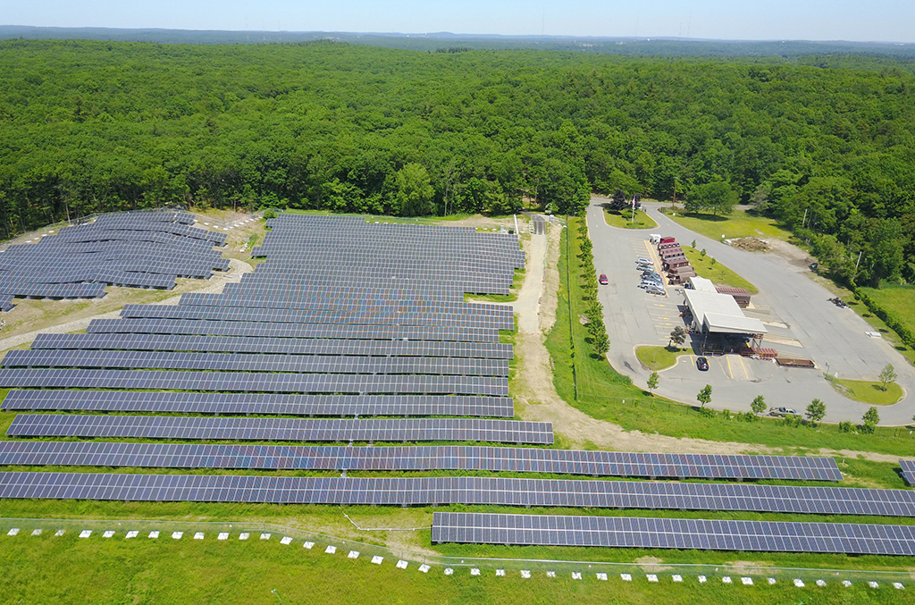 Large solar farm in field by woods